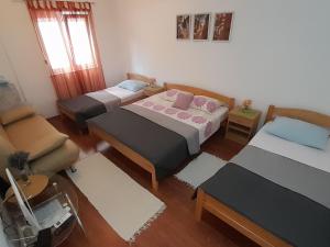 um quarto com três camas e uma cadeira e um sofá em Apartmani "Rebecca" em Neum