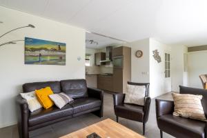 una sala de estar con un sofá y dos sillas en Landhuis Tempelierweg 23, en Den Burg