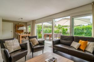 Una sala de estar con un sofá y sillas y una mesa. en Landhuis Tempelierweg 23, en Den Burg