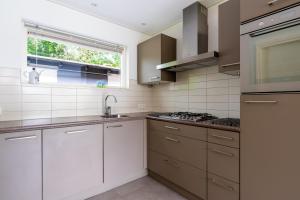 Una cocina con gabinetes blancos y un fregadero y una ventana. en Landhuis Tempelierweg 23, en Den Burg 14 fotos más