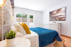 a bedroom with a bed with a blue blanket and yellow pillows at Casa Abril in Santanyi