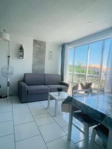 uma sala de estar com um sofá e uma mesa em Superbe appartement 6 personnes avec piscine secteur Richelieu, à 400m de la plage et à 650m du centre port em Cap d'Agde