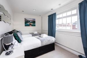 a white bedroom with a bed and a window at Elite 2 Bedroom House in Chadwell Heath/ Romford with Free Wifi and Parking upto 4 guests in Goodmayes