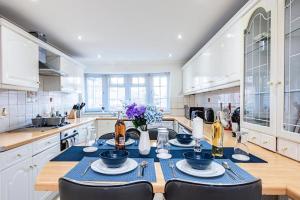 Elite 2 Bedroom House in Chadwell Heath/ Romford with Free Wifi and Parking upto 4 guests في Goodmayes: مطبخ مع طاولة مع قطعة قماش من الطاولة الزرقاء