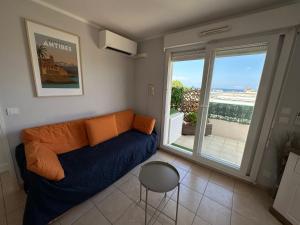 een woonkamer met een bank en een groot raam bij Superbe appartement ensoleillé - Vue mer, Clim et Parking in Villeneuve-Loubet