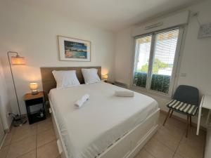 een slaapkamer met een groot wit bed en een raam bij Superbe appartement ensoleillé - Vue mer, Clim et Parking in Villeneuve-Loubet