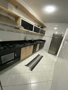 eine Küche mit Spüle und Herd oberen Backofen in der Unterkunft Apto Moderno com Churrasqueira Gourmet, apenas 150m da Praia in Praia Grande + 11 Fotos