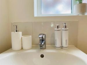 ein Waschbecken mit 2 Flaschen und einem Wasserhahn im Bad in der Unterkunft Modern, Stylish and Central Home in Manchester