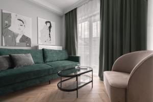 a living room with a green couch and a chair at APARTIO ROOMS Gliwice in Gliwice