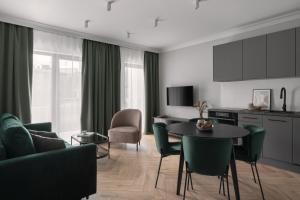 a living room with a table and green chairs at APARTIO ROOMS Gliwice in Gliwice