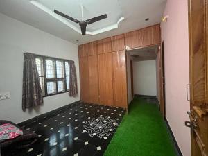 a room with a ceiling fan and green carpet at Vacation Rental Home in Kondapalle