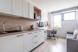 - une cuisine avec des placards blancs et un bureau dans la chambre dans l'établissement RentPlanet - Studio Dyrekcyjna, à Wrocław