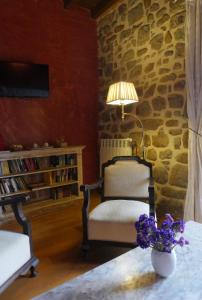 Cette chambre dispose d'une chaise et d'une table avec un vase de fleurs. dans l'établissement Hotel Palacio La Cajiga, à Abándames