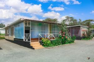 a small house with glass windows and some plants at Lakewalk Cabin in Naivasha