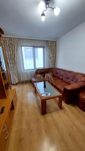 a living room with a brown leather couch and a coffee table at Апартамент Радост in Bansko