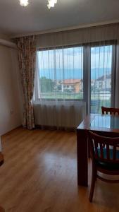 a living room with a table and a large window at Апартамент Радост in Bansko