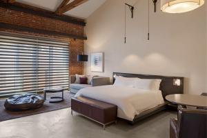 a bedroom with a bed and a chair and a table at HOTEL CERRO, Autograph Collection in San Luis Obispo
