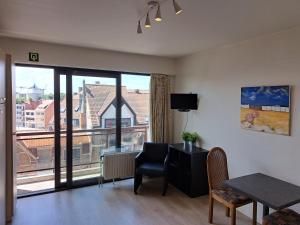a living room with a table and a large window at THOGE Koksijde in Koksijde