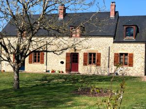 uma casa de tijolos com uma porta vermelha e uma árvore em Bassin aux nénuphars em Crux-la-Ville