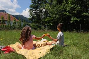 deux enfants assis sur une couverture dans l'herbe dans l'établissement Zen House Bran, à Bran