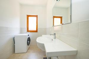 Baño blanco con lavabo y espejo en Affitti Brevi Toscana - Ospitalità a Fonteblanda, en Fonteblanda