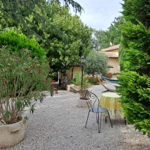 einen Garten mit einem Tisch, Stühlen und Pflanzen in der Unterkunft Le gîte Calluna in Sablet