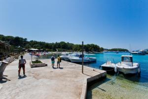 three people standing on a dock with boats in the water at Robinson house T'n'T in Hvar