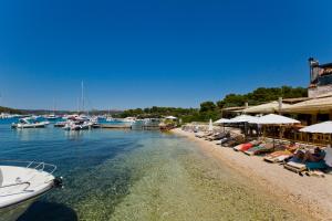 a group of people sitting on a beach with boats at Robinson house T'n'T in Hvar