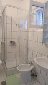 a white bathroom with a shower and a sink at Apartments Veni Up in Starigrad