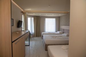a hotel room with two beds and a desk at Hotel Dyrrah in Durrës