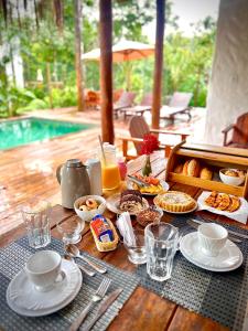 una mesa con comida para el desayuno y bebidas en ella en Villa Sagui Trancoso en Trancoso