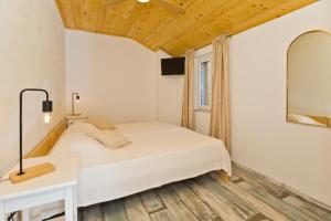 a bedroom with a white bed and a mirror at Robinson house T'n'T in Hvar