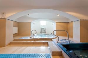 ein Bad mit einem Whirlpool in einem Zimmer mit einem Bogen in der Unterkunft Pałac Pawłowice in Gorz