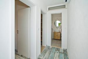 a hallway with white walls and a bathroom with a mirror at Robinson house T'n'T in Hvar