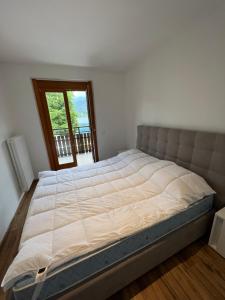 1 cama grande en un dormitorio con ventana en residence Miralago 15 cipat 12727, en Molina di Ledro