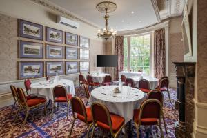 una sala conferenze con tavoli, sedie e lampadario a braccio di Reigate Manor Hotel a Reigate