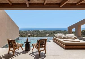 a bedroom with a bed and two chairs on a patio at Memorias Villas and Suites in Vasilikos