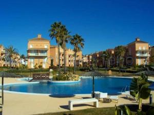 einen Pool mit Stühlen und Sonnenschirmen in einem Resort in der Unterkunft Las Terrazas Islantilla in Huelva