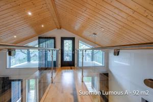 Habitación grande con techo de madera y barandilla de cristal. en Holiday Apartments Suomun Lumous en Suomutunturi