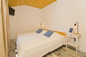 a bedroom with a white bed with blue pillows at Robinson house T'n'T in Hvar
