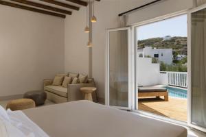 a bedroom with a bed and a couch and a balcony at Andros Moments Suites in Batsi