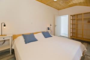 um quarto com uma grande cama branca com almofadas azuis em Robinson house T'n'T em Hvar