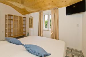 a bedroom with a white bed with blue pillows on it at Robinson house T'n'T in Hvar