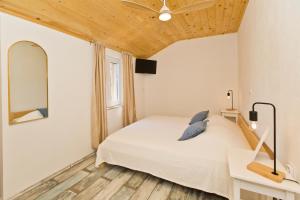 a bedroom with a white bed and a wooden ceiling at Robinson house T'n'T in Hvar