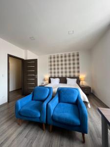 a bedroom with a bed and two blue chairs at Hotel Residence Spalena in Prague