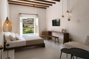a bedroom with a bed and a desk and a window at Andros Moments Suites in Batsi +36 photos