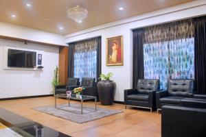 una sala de espera con sillas de cuero negro y una mesa en President Hotel, en Mysore