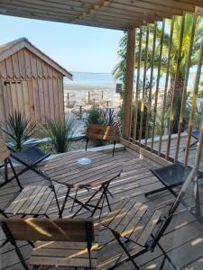 une terrasse en bois avec des chaises, une table et la plage dans l'établissement Hôtel L'Albatros, à Saint-Trojan-les-Bains