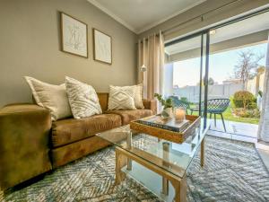 ein Wohnzimmer mit einem Sofa und einem Glastisch in der Unterkunft Garden Unit Inverter,nespresso,blender,netflix in Johannesburg