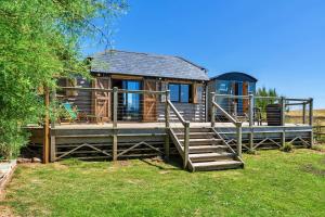 a large wooden cabin with stairs and a house at Finest Retreats - Driftwood in Poundstock